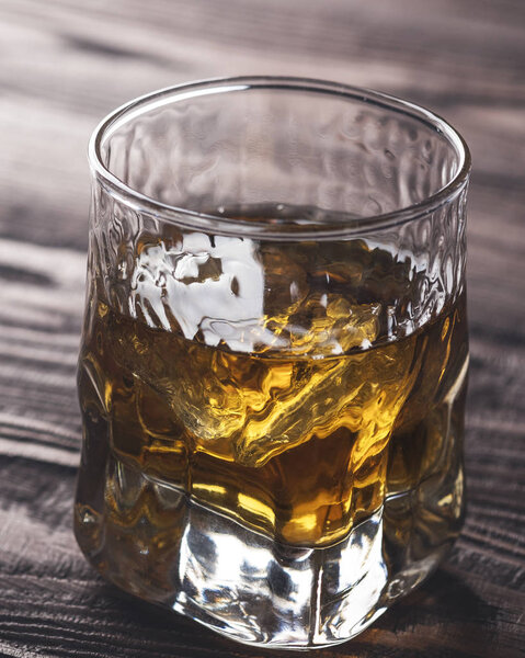 Виски со льдом в стакане на деревенском деревянном фоне. Крупный план
