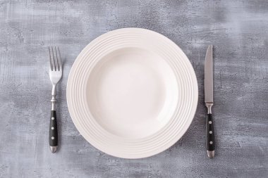 Çatal ve bıçakla servis edilen boş yuvarlak beyaz tabak. Üst Manzara. Boşluğu kopyala