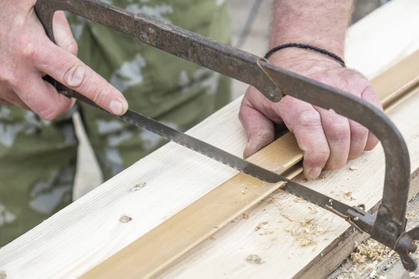 Worker cutting wood with saw. Closeup