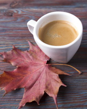 Tahta masada düşmüş yapraklı bir fincan kahve. Sonbahar zamanı