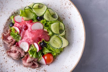 Biftekli, sebzeli ve tabakta kızılcık soslu lezzetli salata. Üst görünüm, metin alanı