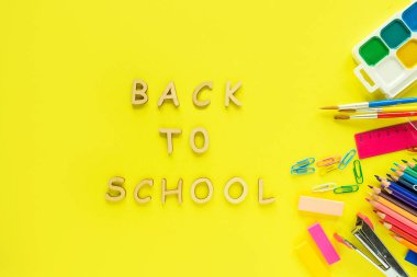 Okulun arka bahçesine. Sarı arka planda okul malzemeleri var..  