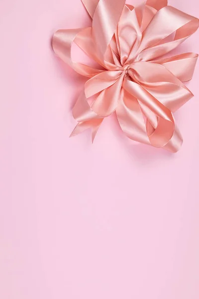 Satin pink bow on pink background with space for text.