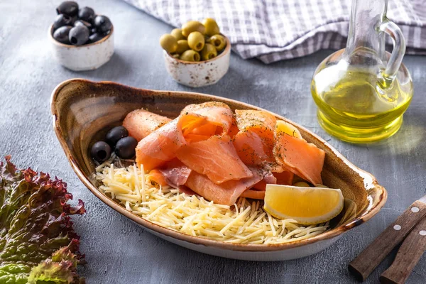 Raw frozen salmon  - stroganina. Raw frozen fish with cheese, lemon and olives on a plate.