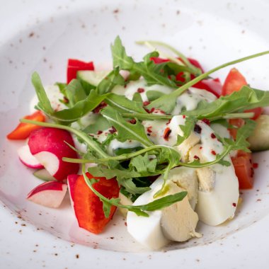 Yumurtalı, domatesli, biberli, yoğurdun altında salatalık ve turplu lezzetli salata. Sebze salatası. Diyet ve sağlıklı yiyecekler. Yakın çekim.