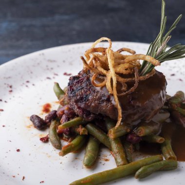 Soslu biftek ve soğan cipsi. Yakın çekim.