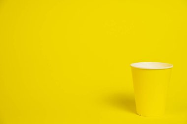 Sarı arka planda sarı kağıt bardak. Metin uzayı