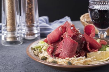 Peynirli, kaparili ve limonlu lezzetli, dondurulmuş et stroganinası. Tabakta dilimlenmiş donmuş çiğ et. Soğuk atıştırmalık