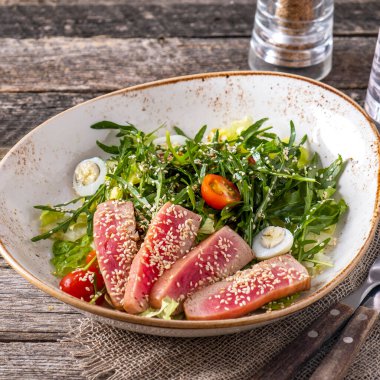 Susamlı ton balığı dilimlenmiş salata roka, domates ve bıldırcın yumurtası.
