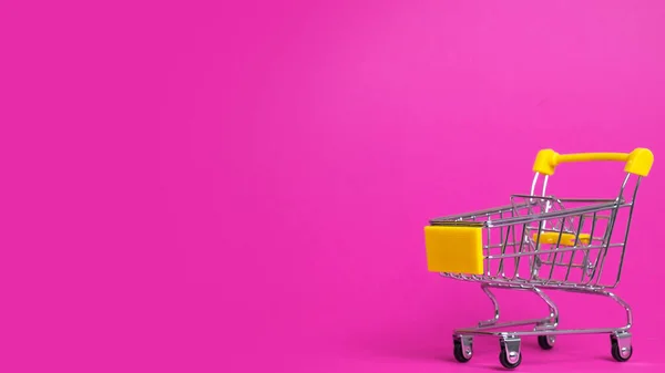 Small shopping cart on pink background. Text space