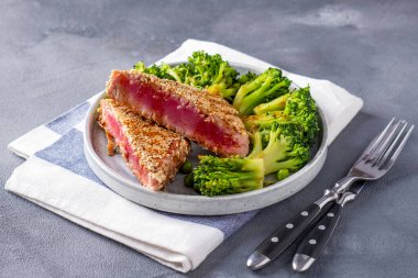 Çatal ve bıçakla servis edilen sebzeli kızarmış ton balığı.