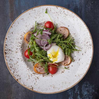 Paskalya yumurtası, roka, vişneli domates ve sosis. Üst görünüm