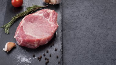 Siyah taşın üzerinde baharatlı çiğ kemik biftek. Üst Manzara. Kopyalama alanı