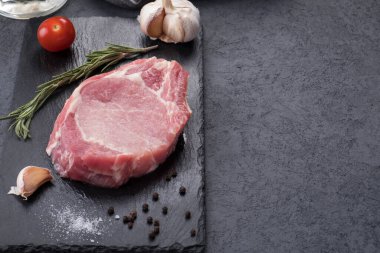 Siyah taşın üzerinde baharatlı çiğ kemik biftek. Pişmemiş et. Üst Manzara. Kopyalama alanı