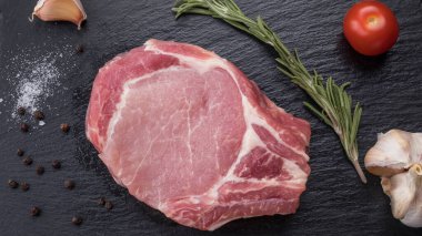Siyah taşın üzerinde baharatlı çiğ kemik biftek. Üst Manzara. Yakın çekim.
