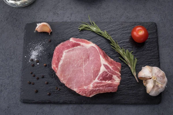 Siyah taşın üzerinde baharatlı çiğ kemik biftek. Pişmemiş et. Üst görünüm. 