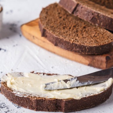 Tereyağlı dilimlenmiş ekmek ve arka planda bıçak. Yakın çekim.