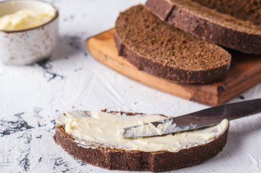 Beyaz arkaplanda tereyağlı dilimlenmiş ekmek. 