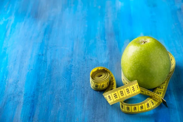 Diet life loss weight concept. Green apple and measure tap with space for text