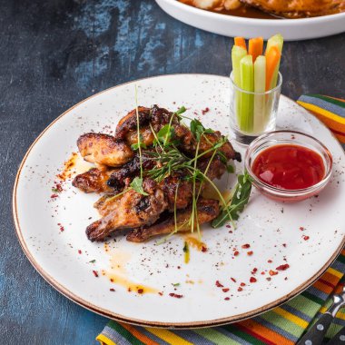 Ketçap, kereviz ve havuçla servis edilen tavuk kanatları.