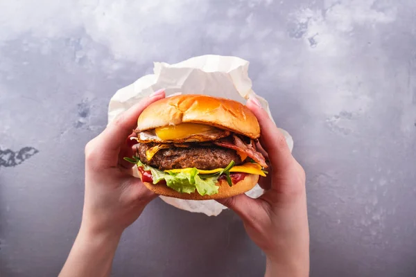 Lezzetli sığır burger ve sahanda yumurta tutan kadın elleri. Üst Manzara. Fast food. Yaşam biçimi