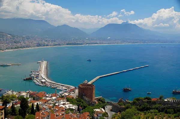 Vista sobre uma costa marítima mediterrânea na cidade turca de Alanya com montanhas nebulosas sob nuvens cúmplices no horizonte e a famosa Torre Vermelha em primeiro plano — Fotografia de Stock