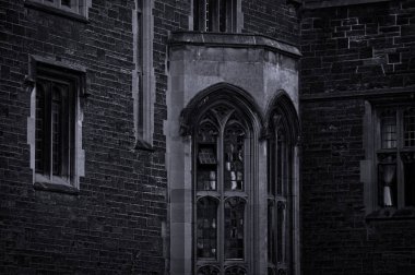 Akşam alacakaranlıkta taş duvarlar ve defne penceresi ile eski bir gotik binanın dış