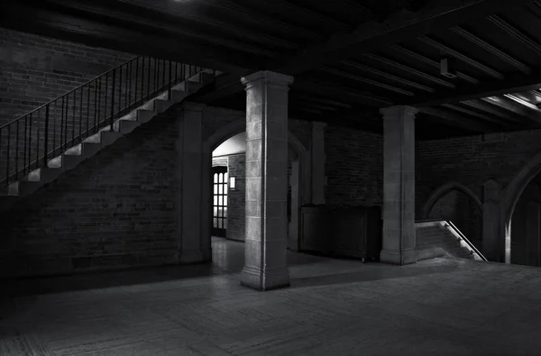 Vista interior de un antiguo edificio con columnas y escalera con algunos haces de luz en un entorno oscuro —  Fotos de Stock