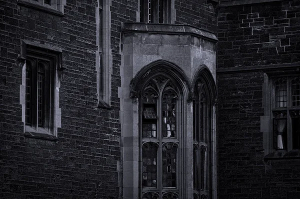 Exterior of an old gothic building with stone walls and bay window in the evening dusk — Stock Photo, Image