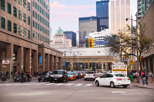Торонто, Канада - 05 20 2018: Движение на пересечении Bay Street и Queens Quay в центре Торонто в солнечный день. Бэй-стрит является центром финансового района Торонто и часто используется для

