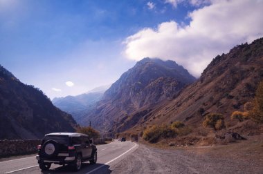 Görkemli dağ manzarası-parlak bulutlu gökyüzü altında Büyük Kafkas Sıradağları arasında kahverengimsi sonbahar montains arasında dar bir yol