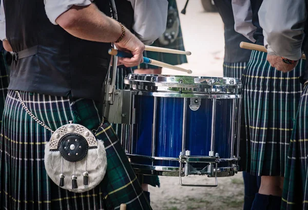 Primo piano del tradizionale tamburo scozzese e le mani di un batterista che indossa kilt in banda scozzese suonare all'aperto — Foto Stock