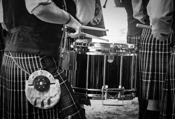 Primo piano del tradizionale tamburo scozzese e le mani di un batterista che indossa kilt in banda scozzese suonare all'aperto — Foto Stock