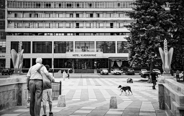 Vladikavkaz, Ρωσία - 07 18 2019: αγκαλιάζει τον παππού και τον εγγονό του που περπατούν μπροστά από το ξενοδοχείο Vladikavkaz στην πρωτεύουσα της Βόρειας Οσετίας — Φωτογραφία Αρχείου