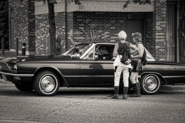 TORONTO, CANADA - 08 18 2018: 1967 Ford Thunderbird 'ün sahibi ile Toronto Danforth Yolu' nun en eski tarihi caddelerinden birinde konuşan hippi tarzı kıyafetler giyen kadınlar.