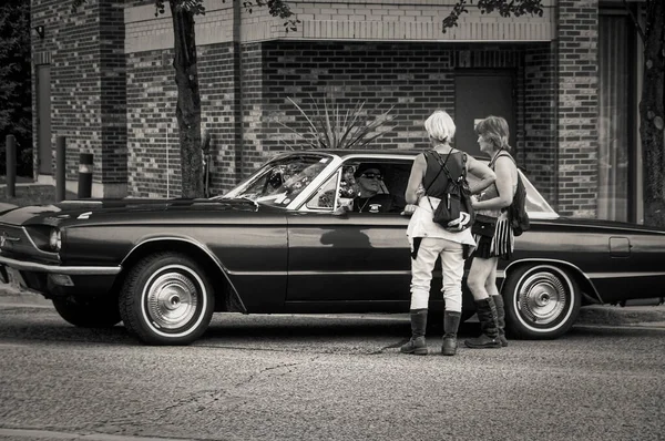 TORONTO, CANADA - 08 18 2018: 1967 Ford Thunderbird 'ün sahibi ile Toronto Danforth Yolu' nun en eski tarihi caddelerinden birinde konuşan hippi tarzı kıyafetler giyen kadınlar.