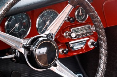 Direksiyon, hız göstergesi, devir, saat göstergeleri, radyo ölçeği, ön paneldeki düğmeler ve düğmeler kırmızı coupe eski spor araba..