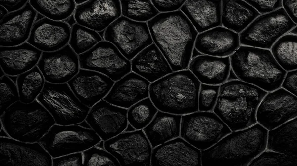 Dark monochrome wall made of stone and cement. Mosaic of rocks used as tiles. Black stone fence. Decorative texture from natural material. Background, pattern, texture.