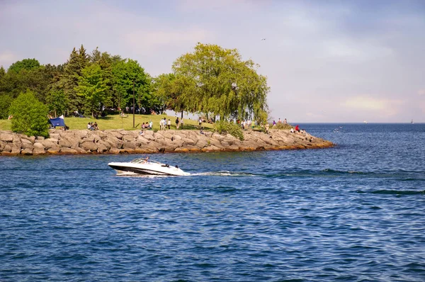 MISSISAUGA,カナダ- 2020年6月10日:ウォーターフロント・トレイルで休息中の人々の前でオンタリオ湖の水に浮かぶモーターボート — ストック写真
