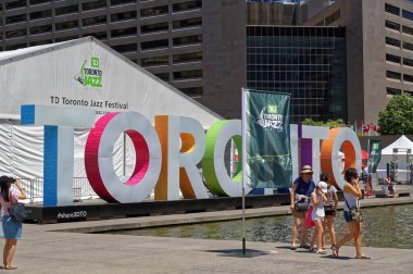 TORONTO, CANADA - 06 27 2016: TORONTO tabelasının önünde yürüyen insanlar ve Nathan Phillips Meydanı 'nda Toronto Caz Festivali' nin konser salonu köşkü