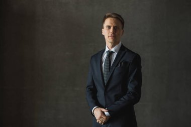 Gri arka plan üzerinde resmi kıyafetli yakışıklı işadamı