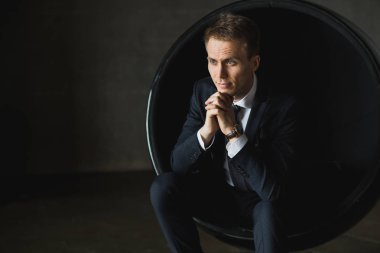 gri arka plan üzerinde sandalyede oturan genç işadamı