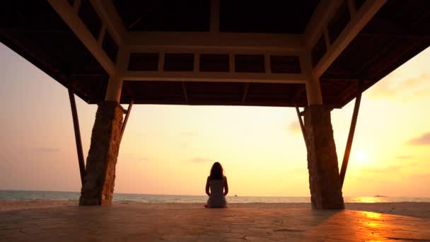 Flickan gör yoga posera i ett buddhistiskt tempel i solnedgången. — Stockvideo