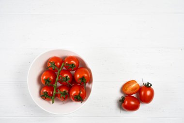 Beyaz ahşap zemin üzerinde bir tabak taze kiraz domates.