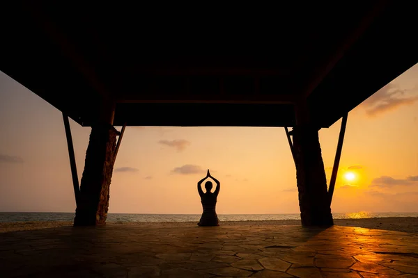 Kız bir Budist tapınağı günbatımında poz yoga yapıyor.