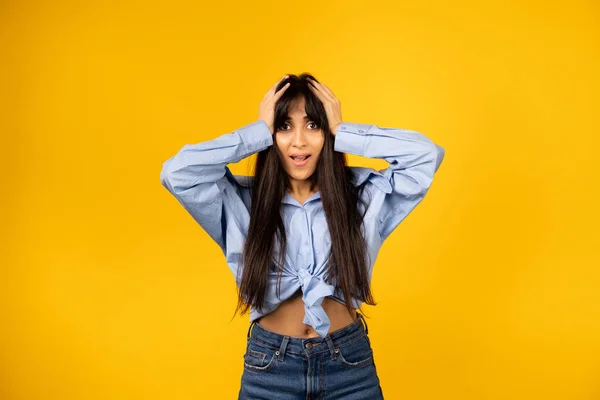 Joven hermosa chica en una camisa azul posando para una foto sobre un fondo amarillo . —  Fotos de Stock