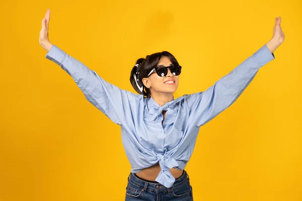 Chica joven con gafas de sol posando para una foto sobre fondo amarillo . —  Fotos de Stock