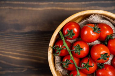 Koyu ahşap arka plan üzerinde bir tabakta taze kiraz domates.