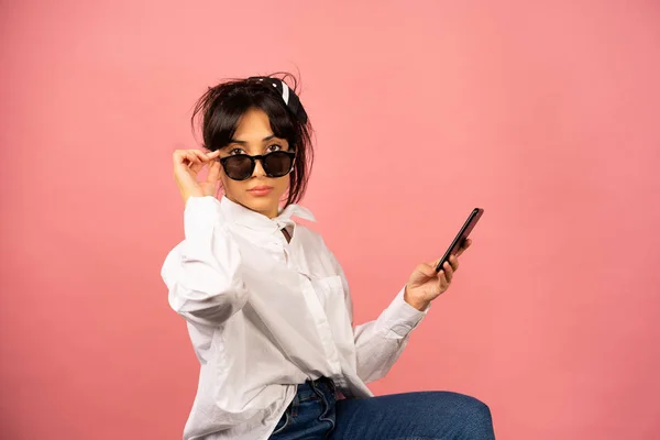 Chica joven en gafas de sol haciendo selfie sobre un fondo rosa . —  Fotos de Stock