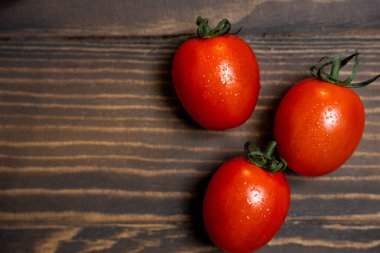 Fresh cherry tomatoes on a dark wood background.